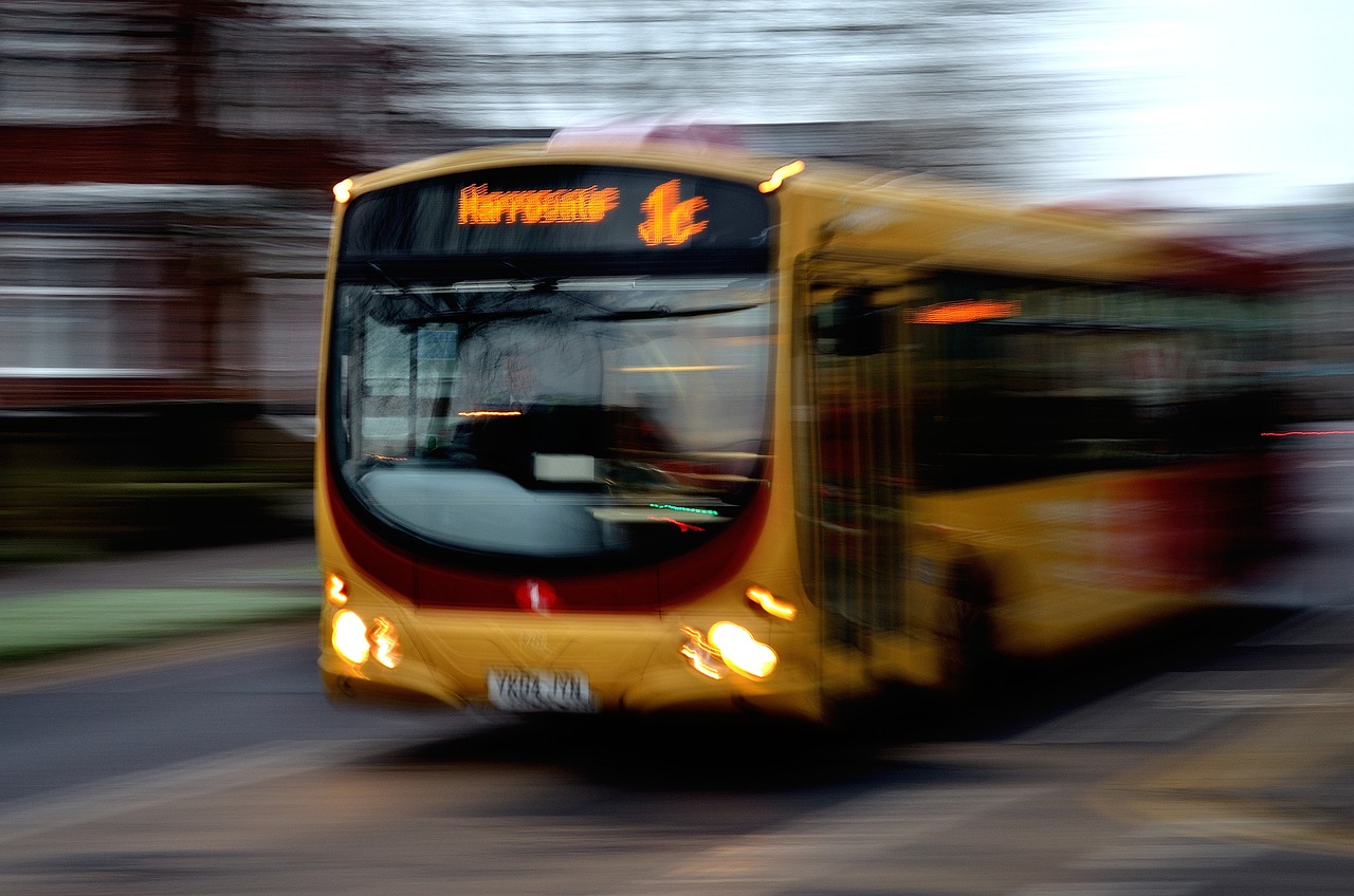 A yellow single-decker bus, moving fast on the road.